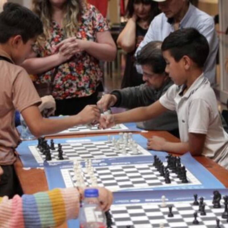 Imagen de niños jugando sobre un tablero de ajedrez hecho de piezas recicladas.