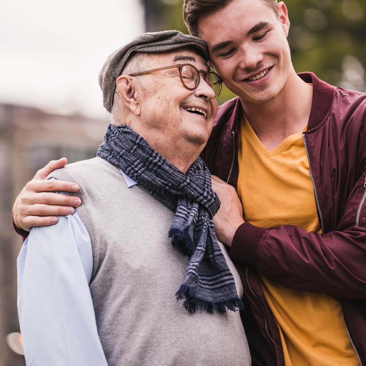 Un hombre mayor y un joven se abrazan sonriendo.